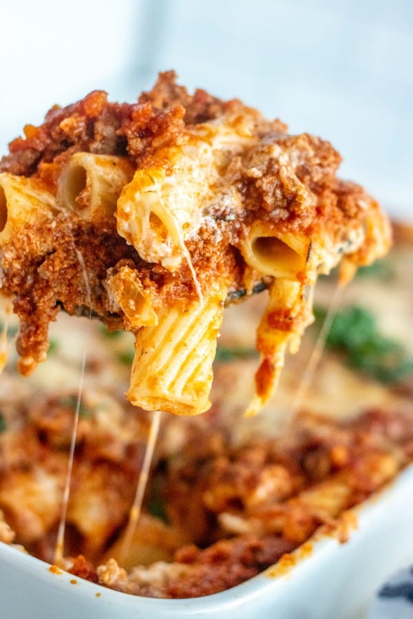 Baked ziti in a white baking dish with a scoop taken out