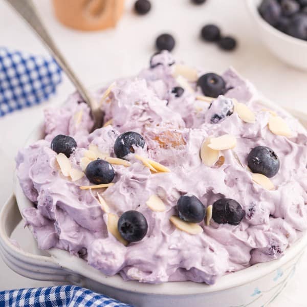 blueberry fluff salad in a white bowl with a blue gingham napkin.