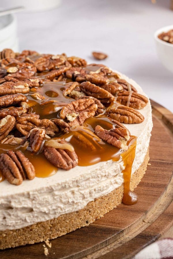 A caramel pecan cheesecake with caramel sauce and pecans on top.