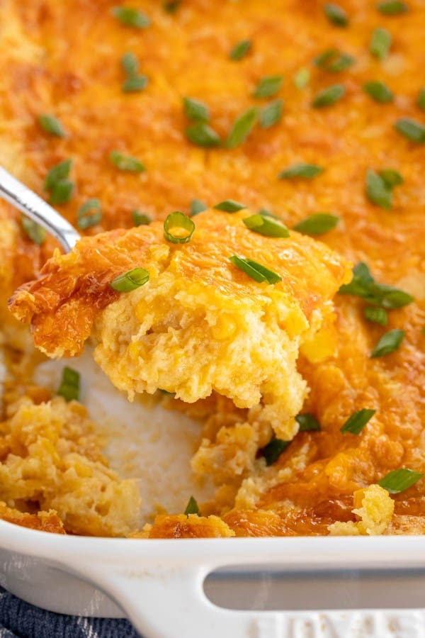 Cheesy corn casserole in a white dish.
