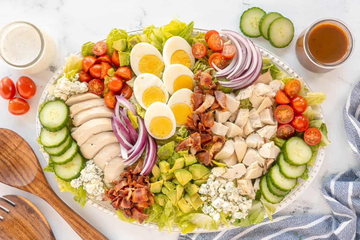 A plate of Cobb salad with chicken, bacon, and eggs.