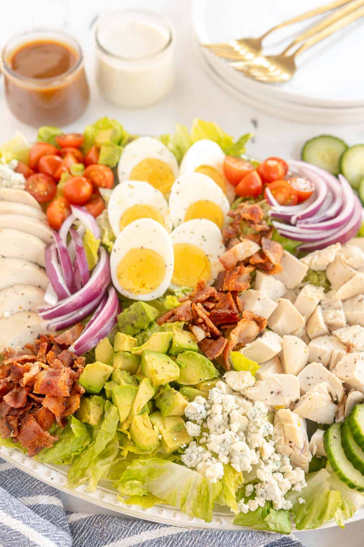 A plate of Cobb salad with chicken, bacon, and eggs.