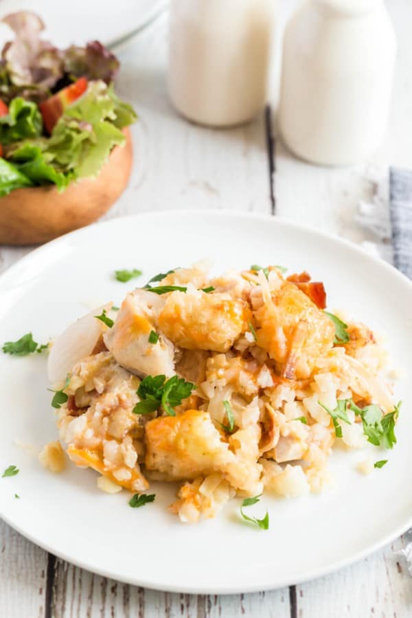 chicken tater tot casserole on a white plate with parsley.