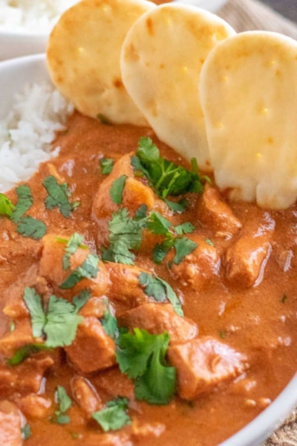 chicken tikka masala in a white bowl with mini naan