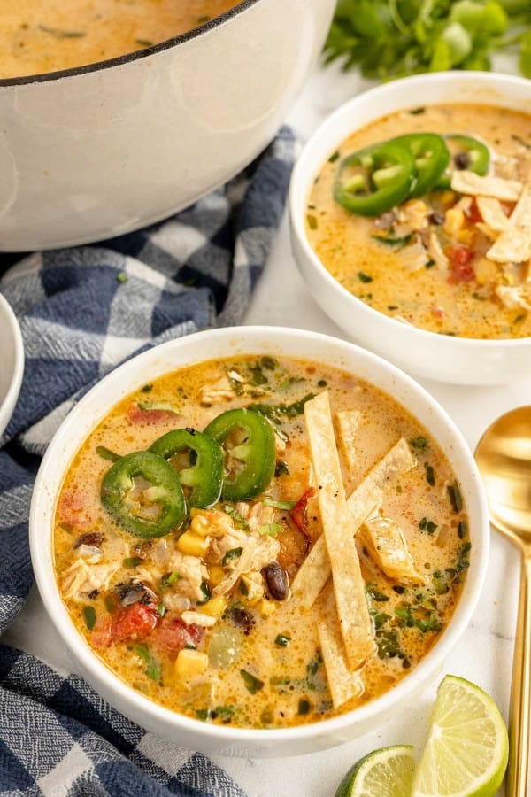 Bowls of chicken tortilla soup with tortilla chips and jalapenos and limes.