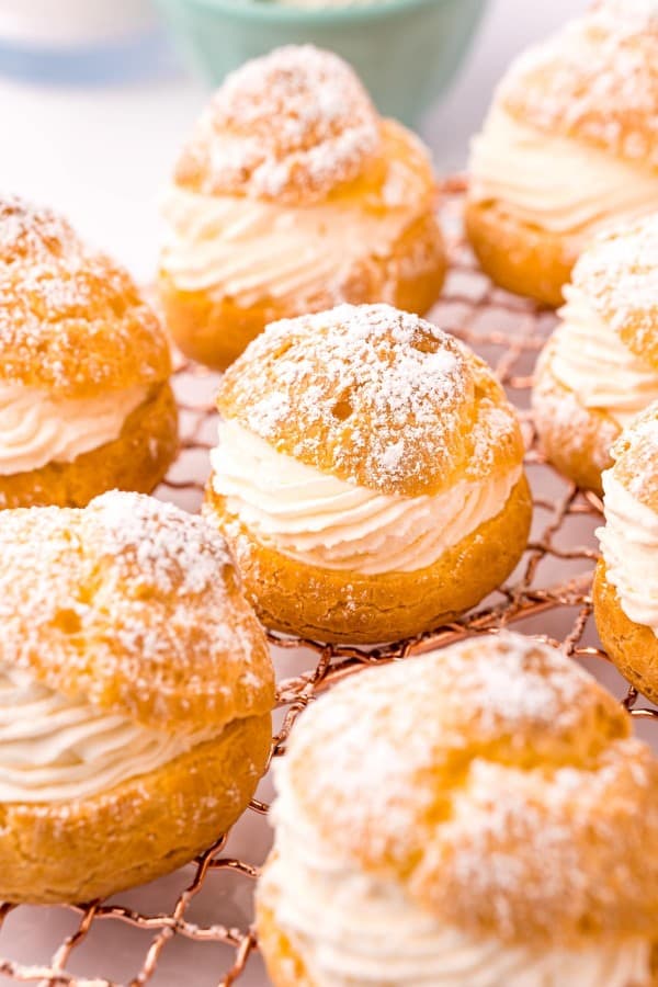 cream puffs filled with whipped cream on a wire rack.