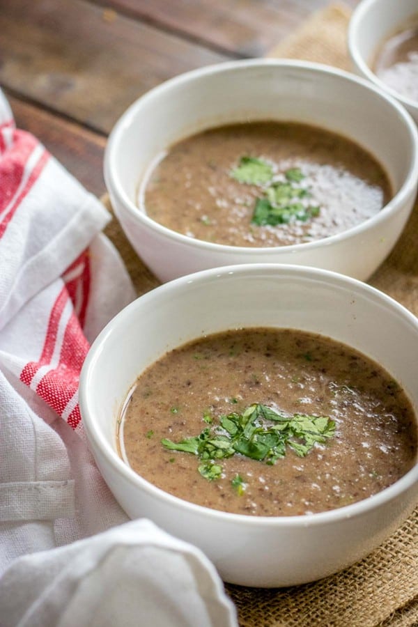 2 bowls of black bean soup in white bowls