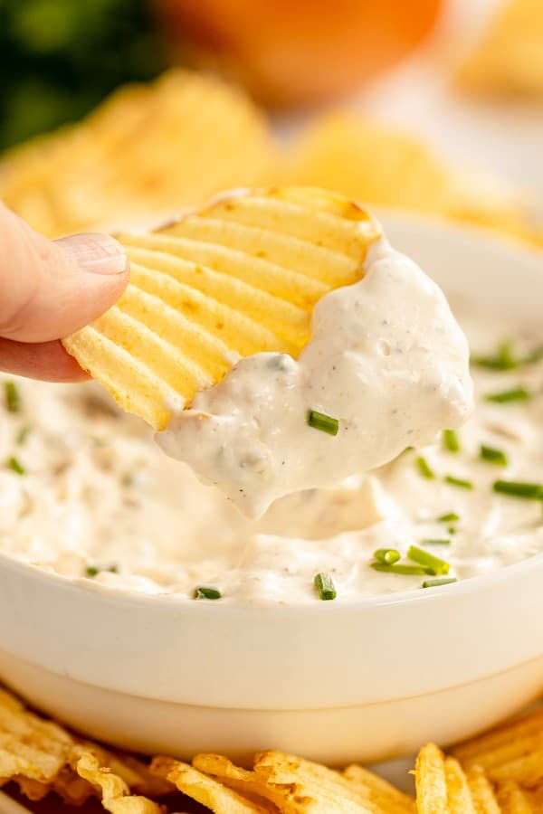 french onion dip in a bowl with a chip grabbing dip.