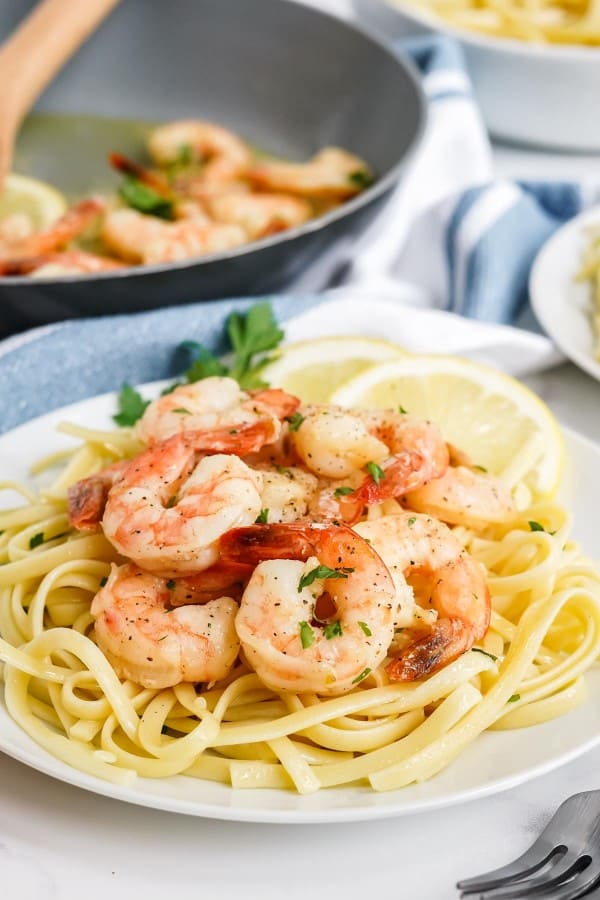 garlic butter shrimp on a white plate over spaghetti