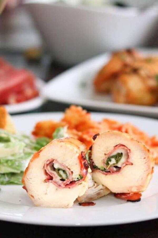 chicken roll ups on a white plate with sides
