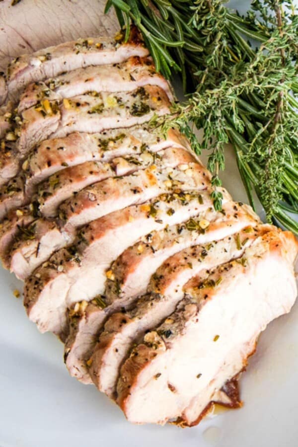 roasted pork loin in slices with sprigs of thyme