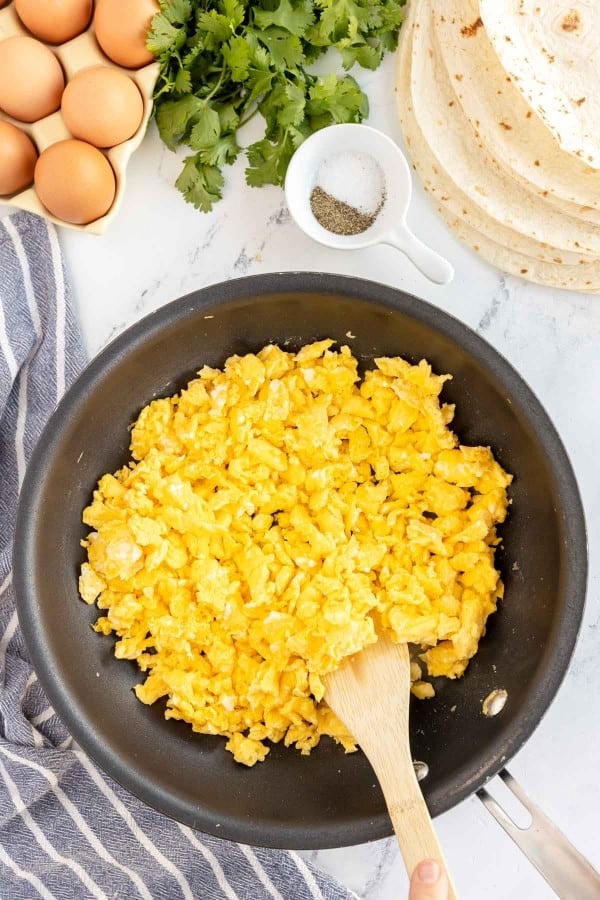 skillet with scrambled eggs and a wooden spoon.