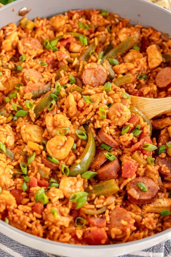 jambalaya in a skillet with a wooden spoon.
