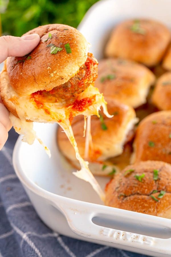 a slider being pulled from a baking dish.