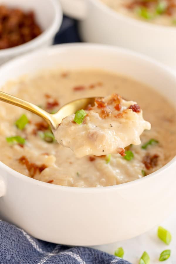 potato cheese soup on a spoon, with a white bowl.