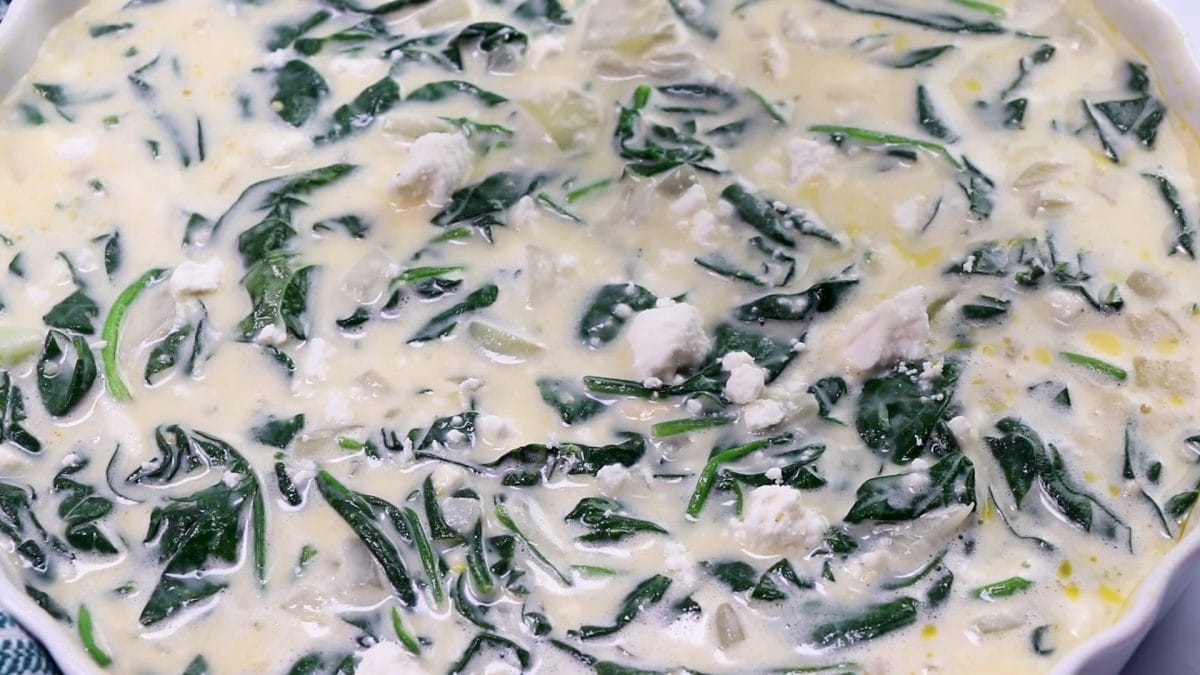 quiche batter in a tart pan, unbaked with feta on top.