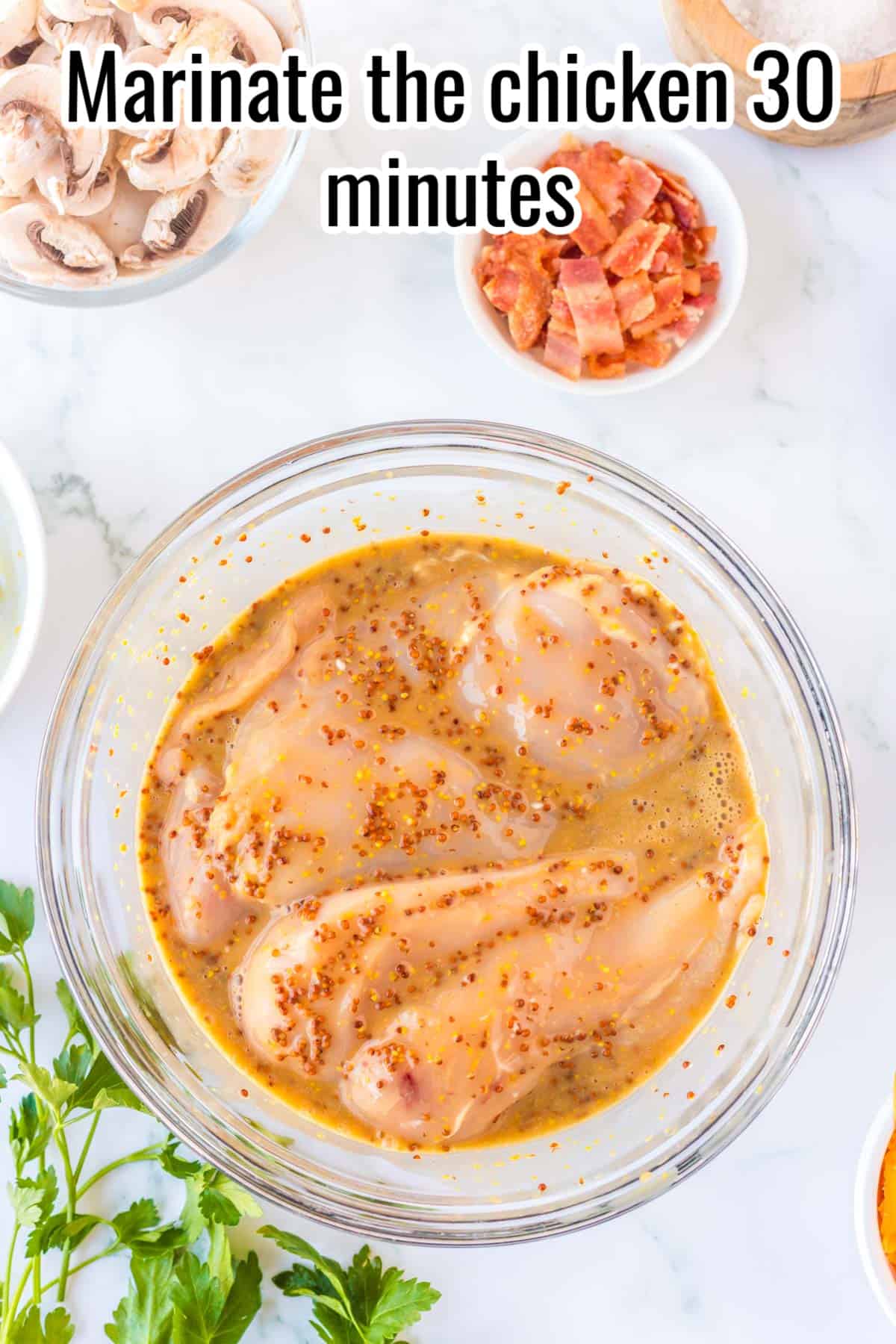 chicken marinating in a glass bowl.