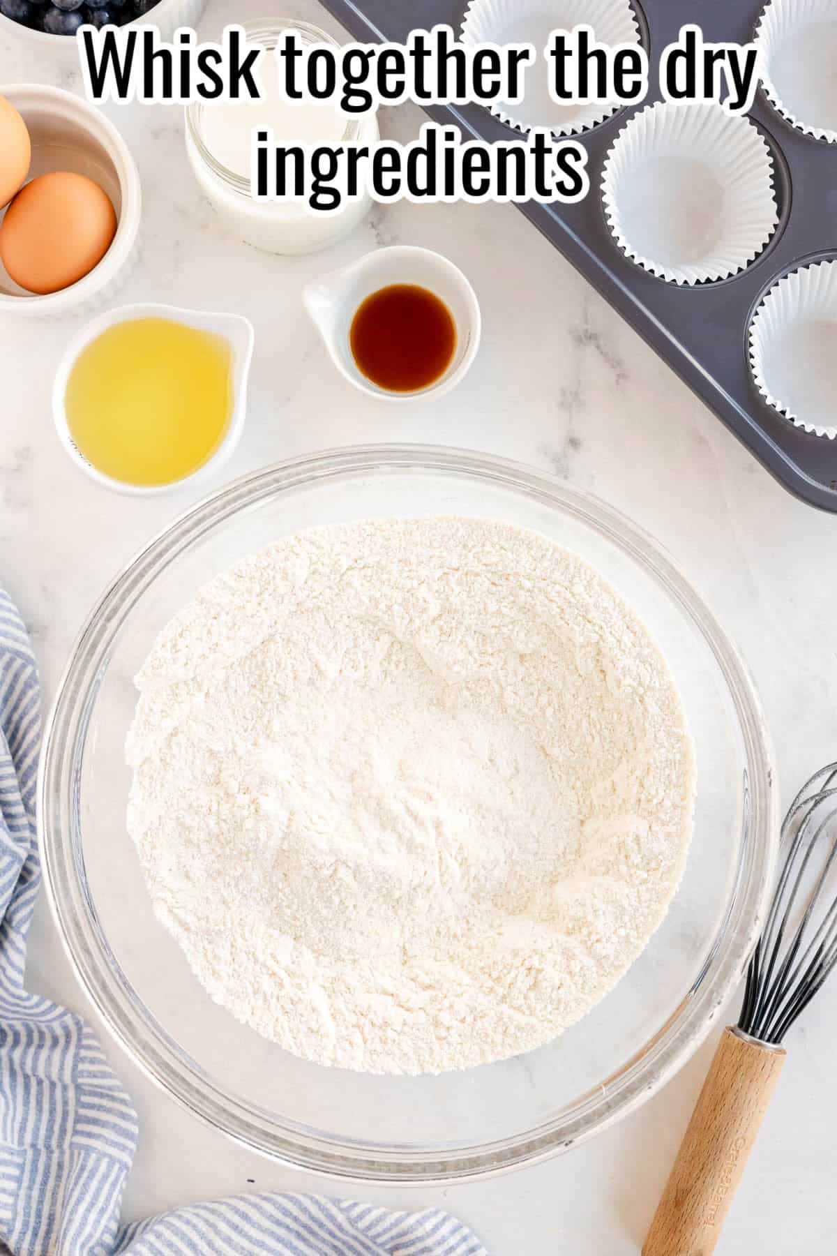 a glass bowl and whisk with dry ingredients for muffins.