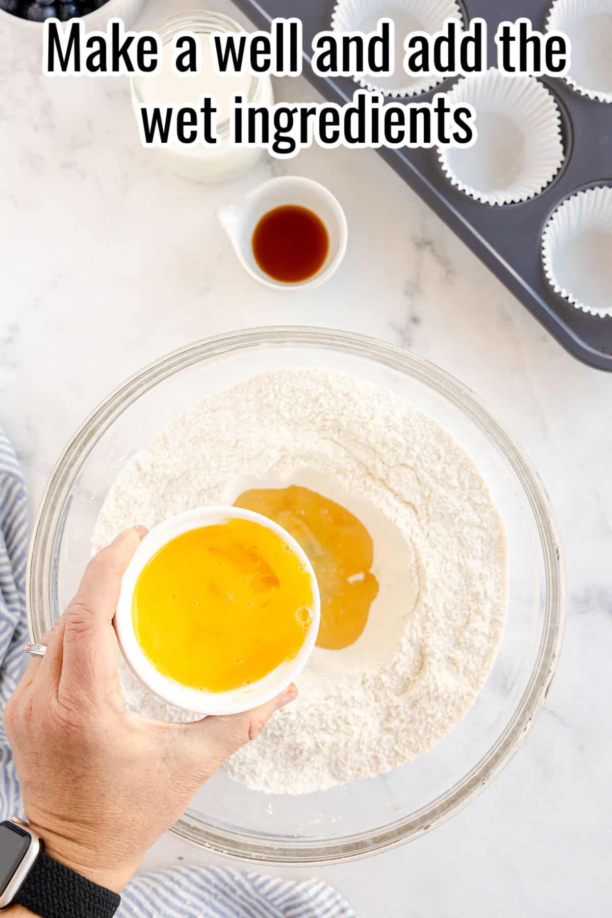 a glass bowl with flour and wet ingredients being added.