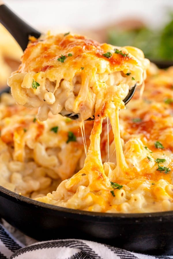cast iron skillet of mac and cheese with a scoop pulling out