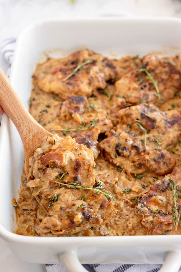 chicken casserole in a white dish with a wooden spoon.
