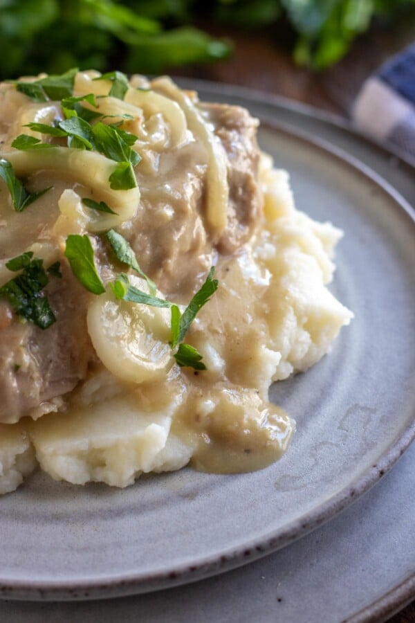 smothered pork chops on a grey plate
