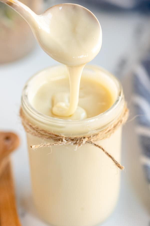homemade sweetened condensed milk on a spoon.