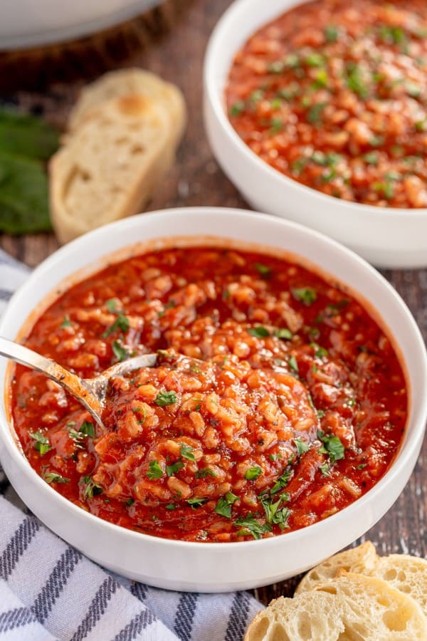 tomato rice soup in a white bowl with bread